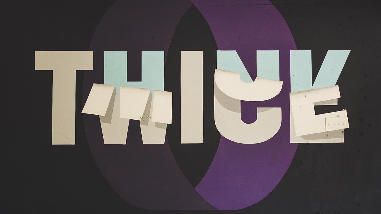 Bold white letters that read "Think Twice" against a textured gray background, implying the importance of carefully considering the decision to rebrand a business.