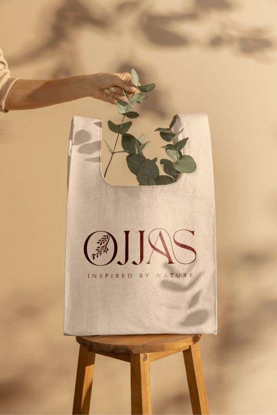 A peach tote with Ojjas logo printed on it, designed by Avval Digital Marketing Company for Ojjas brand